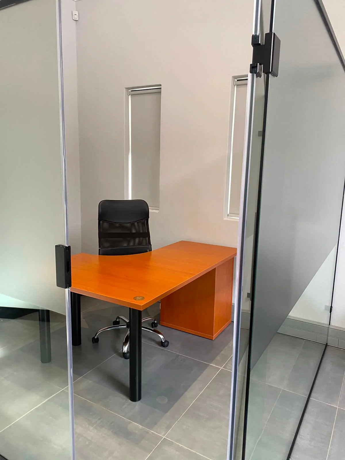 Wooden hot desk and office chair inside a glass-partitioned workspace at 17 Private Road