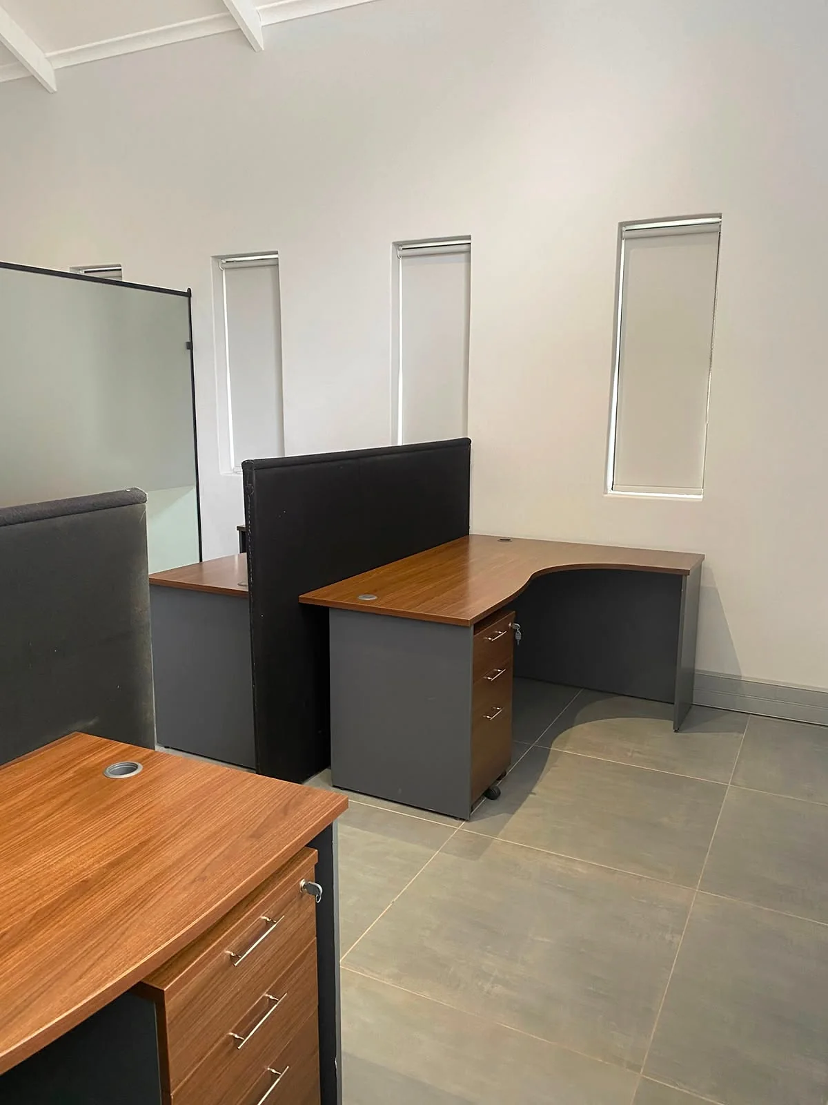 Wooden workstations with privacy dividers beside narrow office windows at 17 Private Road