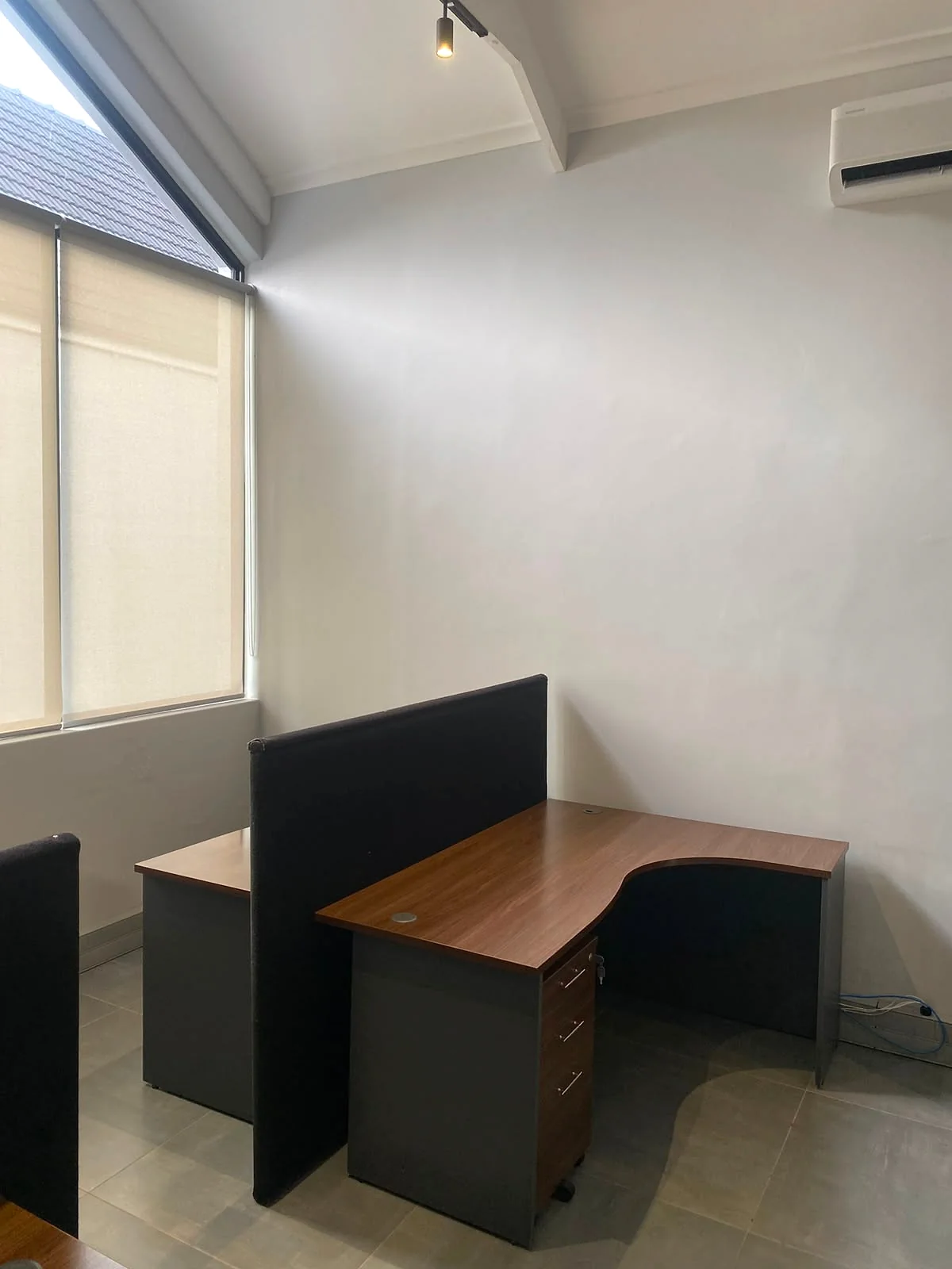 Individual wooden workstation with a privacy divider beside the large window at 17 Private Road